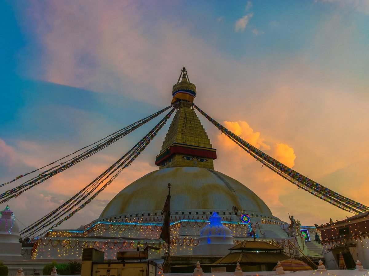 Boudhanath stupa in Kathmandu strung with prayer flags at sunset