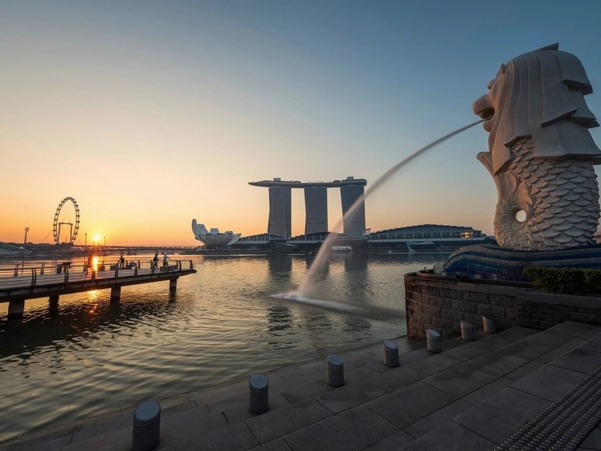 The Merlion spouting water at sunset with Marina Bay Sands behind it